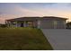 Charming single-story home with a well-manicured lawn and a spacious two-car garage at sunset at 10493 Grail Ave, Englewood, FL 34224