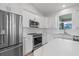 Bright kitchen with stainless steel appliances, white cabinets, and light countertops at 10493 Grail Ave, Englewood, FL 34224