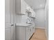Laundry room with white cabinets, marble countertops, window, sink, and a door leading outside at 10493 Grail Ave, Englewood, FL 34224