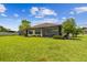 Expansive backyard with lush lawn, tropical palms, colorful flowerbeds, and a screened-in patio for outdoor living at 10816 Wendover Dr, Palmetto, FL 34221