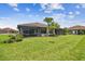 Well-maintained backyard with vibrant green lawn, established palms, and a screened lanai for relaxing outdoors at 10816 Wendover Dr, Palmetto, FL 34221