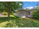 Exterior view of backyard with lush grass, a brick patio, and the side of the house at 1340 Whispering Pines Dr, Clearwater, FL 33764