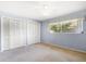 Bedroom showing two large closet doors, a window with curtains, and blue colored walls at 1340 Whispering Pines Dr, Clearwater, FL 33764