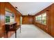 Living room with wood paneling, with a desk and large windows at 1340 Whispering Pines Dr, Clearwater, FL 33764