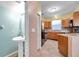 Bathroom with pedestal sink leading to adjacent kitchen with wood cabinetry and appliances at 13777 Forest Lake Dr, Largo, FL 33771
