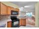 A well-lit kitchen features oak cabinetry, a black electric range, and tiled backsplash at 13777 Forest Lake Dr, Largo, FL 33771