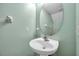 Charming powder room featuring a pedestal sink, oval mirror, and fresh green walls at 13777 Forest Lake Dr, Largo, FL 33771