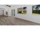 Spacious living room with wood-look floors, white walls, ceiling fan and French doors to the backyard at 15118 Brushwood Dr, Tampa, FL 33624