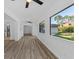 Bright living room with wood-look floors, white walls, ceiling fan and large window to the backyard at 15118 Brushwood Dr, Tampa, FL 33624