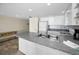 Open kitchen with peninsula, white cabinets, gray countertops, tile backsplash and stainless sink at 19440 Gulf Blvd # 306, Indian Shores, FL 33785