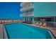 Community outdoor pool with lounge chairs and balcony views to the ocean at 19440 Gulf Blvd # 306, Indian Shores, FL 33785