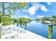 Wooden dock overlooking a tranquil waterway surrounded by lush greenery and clear blue skies at 2250 Mountain Ash Way, New Port Richey, FL 34655