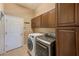 Functional laundry room with washer, dryer, and dark wooden cabinets for ample storage at 2250 Mountain Ash Way, New Port Richey, FL 34655