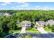An aerial view of two homes in a lush community surrounded by dense trees under a partly cloudy sky at 27549 Stonecreek Way, Wesley Chapel, FL 33544