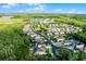 Aerial view showcasing a residential community with houses by a lake surrounded by lush greenery and dense trees at 27549 Stonecreek Way, Wesley Chapel, FL 33544