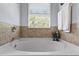 Relaxing bathroom showcasing a soaking tub with tile surround, a large window, and neutral walls at 27549 Stonecreek Way, Wesley Chapel, FL 33544