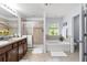 Bright bathroom featuring double vanities, a separate tub, and a glass-enclosed shower at 27549 Stonecreek Way, Wesley Chapel, FL 33544