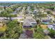 A broad aerial view shows the house, deck, pond, and surrounding neighborhood nestled among verdant trees at 284 Peninsula Ave, Tarpon Springs, FL 34689