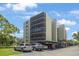 Low-angle view of a multi-story condo building with covered parking beneath it in front of lush, green trees at 2900 Cove Cay Dr # 1B, Clearwater, FL 33760