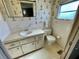 Bathroom featuring a white sink, toilet, mirror and an accent wallpaper at 34461 Cactus Dr, Pinellas Park, FL 33781