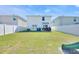 Spacious backyard featuring a large grassy area, patio seating, and a white fence at 636 Sunlit Coral St, Ruskin, FL 33570