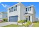 Inviting two-story home with a covered entry, a blue garage door, and professionally landscaped front yard at 636 Sunlit Coral St, Ruskin, FL 33570
