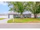Charming single-story home with gray siding, a well-manicured lawn, and mature trees in a residential neighborhood at 7111 13Th E St, Sarasota, FL 34243
