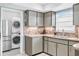 Stylish kitchen features gray cabinets, tiled backsplash, stainless steel appliances, and a laundry area at 7111 13Th E St, Sarasota, FL 34243