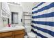 Bathroom with a white sink, wooden cabinet, mirror, and blue and white striped shower curtain at 8125 Stone Path Way, Tampa, FL 33647