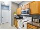 Well-lit kitchen featuring light wood cabinets, a stainless steel microwave, and a white range at 8125 Stone Path Way, Tampa, FL 33647