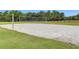 Outdoor sand volleyball court surrounded by grass and fencing and green trees in the background at 8125 Stone Path Way, Tampa, FL 33647