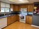Kitchen with wood cabinets, white appliances and hardwood floor, offering functional space at 825 S Village N Dr # 201, St Petersburg, FL 33716