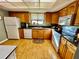 Traditional kitchen with wooden cabinets, white appliances, black countertops, and light wood flooring at 825 S Village N Dr # 201, St Petersburg, FL 33716