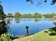 Scenic view of a pond with fountain, blue skies, lush greenery, and nearby buildings, under a clear blue sky at 825 S Village N Dr # 201, St Petersburg, FL 33716