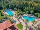 This aerial view shows resort-style pools surrounded by palm trees, lounge chairs, and lush landscaping at 8628 Eagle Brook Dr, Land O Lakes, FL 34638