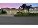 Beautiful single-Gathering home, well-manicured lawn, mature palm trees, and a three-car garage at dusk at 8628 Eagle Brook Dr, Land O Lakes, FL 34638