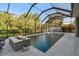 A sparkling screened-in pool featuring a fire pit and lush landscaping, perfect for relaxing and entertaining at 8628 Eagle Brook Dr, Land O Lakes, FL 34638