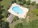 Aerial shot shows a large community pool with lounge chairs, tables, and a pool house surrounded by green space at 1023 Orca Ct, Holiday, FL 34691