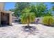 Paver patio featuring a palm tree in the center, surrounded by lush greenery and outdoor seating at 1023 Orca Ct, Holiday, FL 34691