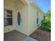 Close up of the front door with an oval glass pane, brick landing and textured stucco walls at 10809 Collar Dr, San Antonio, FL 33576