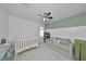 Neutral colored room with white crib, light blue dresser, grey couch, and ceiling fan at 10947 Verawood Dr, Riverview, FL 33579