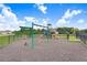 Community playground with swings and slides in a fenced area with a soft ground surface at 12168 Lily Magnolia Ln, Riverview, FL 33569