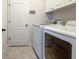 Well-lit laundry room featuring a modern washer and dryer, tile flooring and white cabinets at 12206 Blue Pacific Dr, Riverview, FL 33579