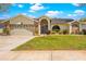 Inviting home with a well-kept lawn, brick accents, arched entryway, and an attached two-car garage at 18836 Green Park Rd, Hudson, FL 34667