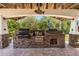 Outdoor kitchen with multiple grills, stone accents, and wood storage, perfect for entertaining at 18836 Green Park Rd, Hudson, FL 34667