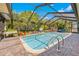 Large backyard pool with screened enclosure, surrounded by brick pavers, invites relaxation and outdoor enjoyment at 18836 Green Park Rd, Hudson, FL 34667