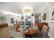 Dining area featuring a wood table, wicker chairs, and a view of the open kitchen with a modern chandelier at 19817 Gulf Blvd # 602, Indian Shores, FL 33785