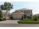 Charming two-story home featuring a well-manicured lawn, palm trees, and an attached two-car garage at 27094 Carolina Astor, Wesley Chapel, FL 33544