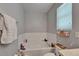Bathroom featuring a white soaking tub with tile surround, a window with blinds, and neutral wall color at 2915 Royal Tuscan Ln, Valrico, FL 33594
