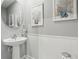 Clean and simple powder room featuring a pedestal sink, white wainscoting, and coastal-themed decor at 3158 Victoria Inlet Dr, Holiday, FL 34691